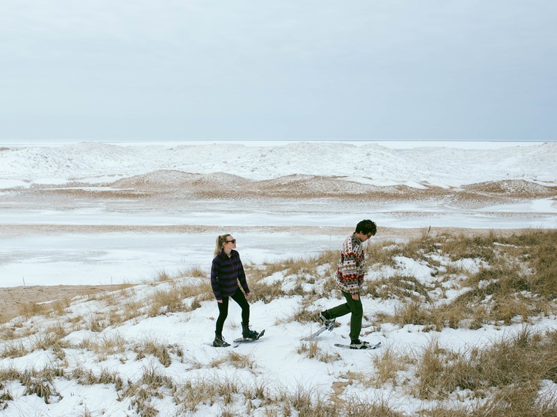Couple snowshoeing on dunes in the winter