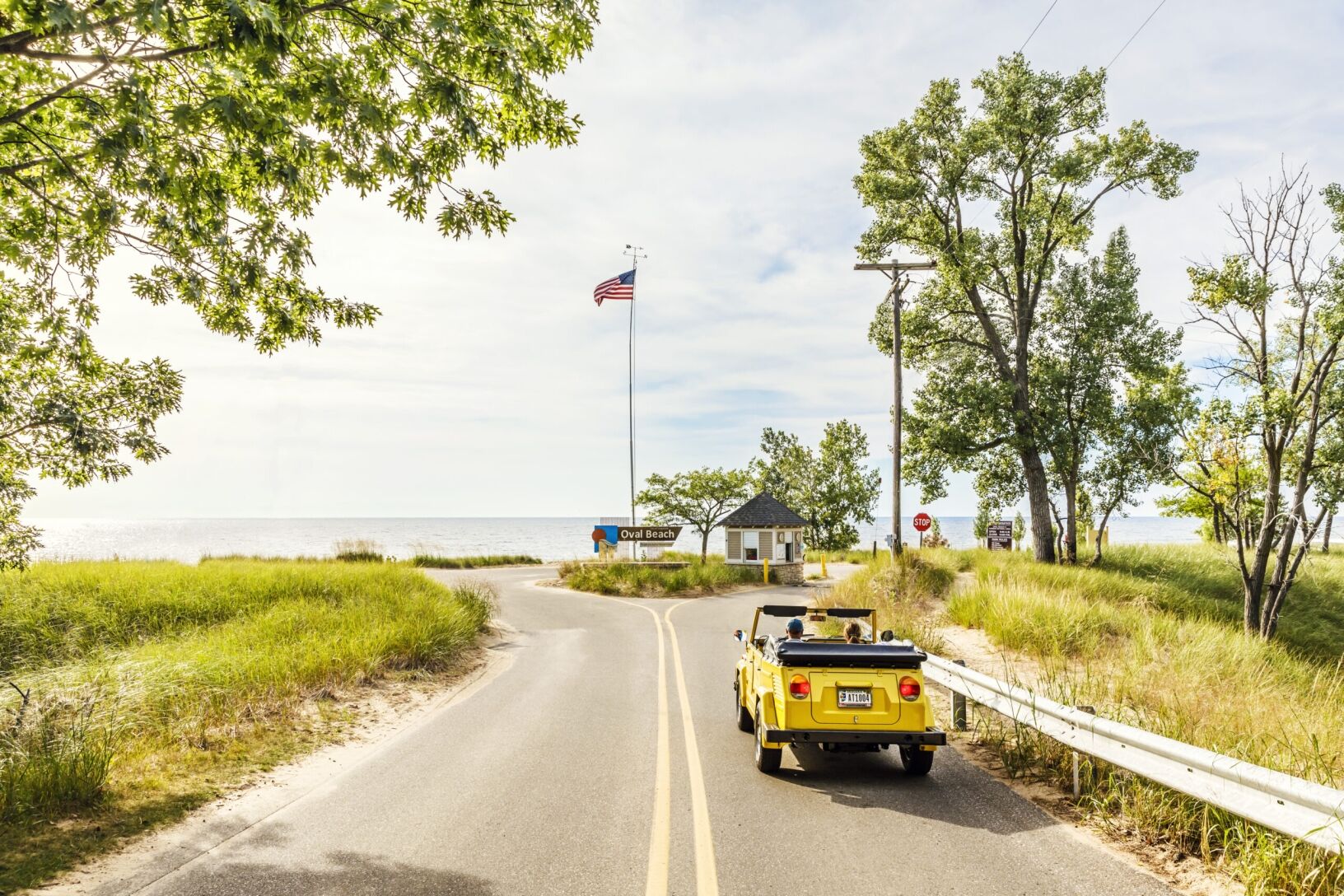 A yellow car driving toward the entrance of Oval Beach.