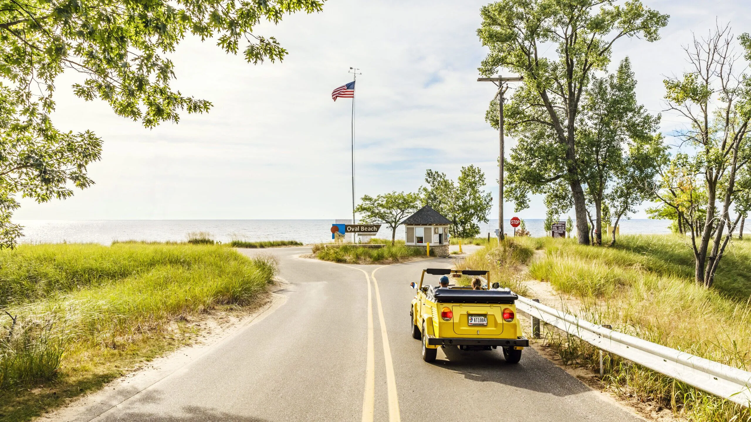 A yellow car driving toward the entrance of Oval Beach.