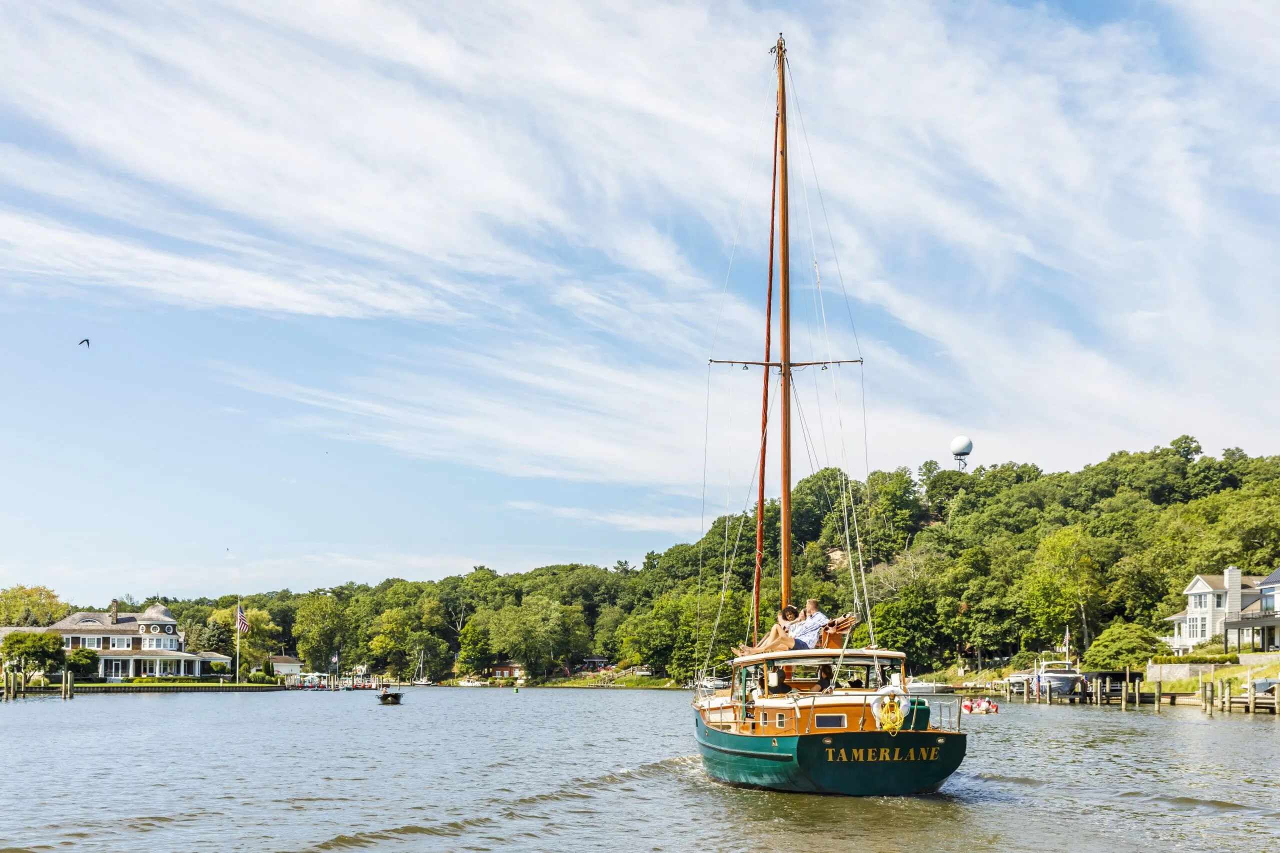 Two friends on top of a sail boat going down the channel. Lake houses and Mt. Baldhead are in the distance.