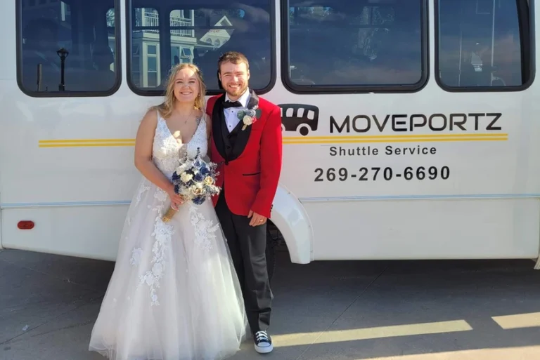 A bride and groom standing outside the Moveportz Shuttle and Private Car Service bus.