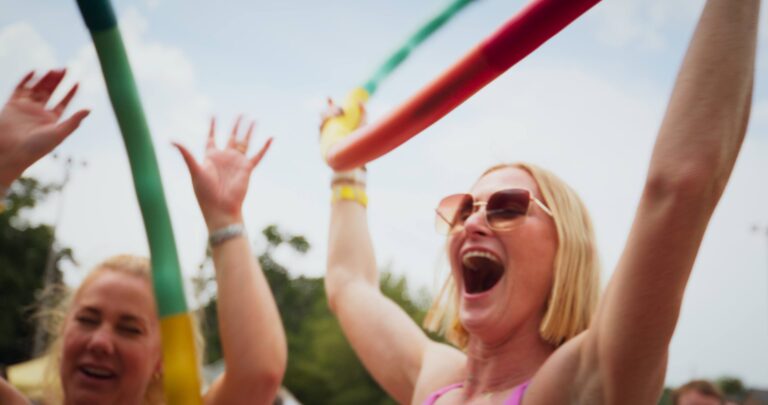 A woman in sunglasses holding a hula hoop and dancing at the Saugatuck Pride Festival.