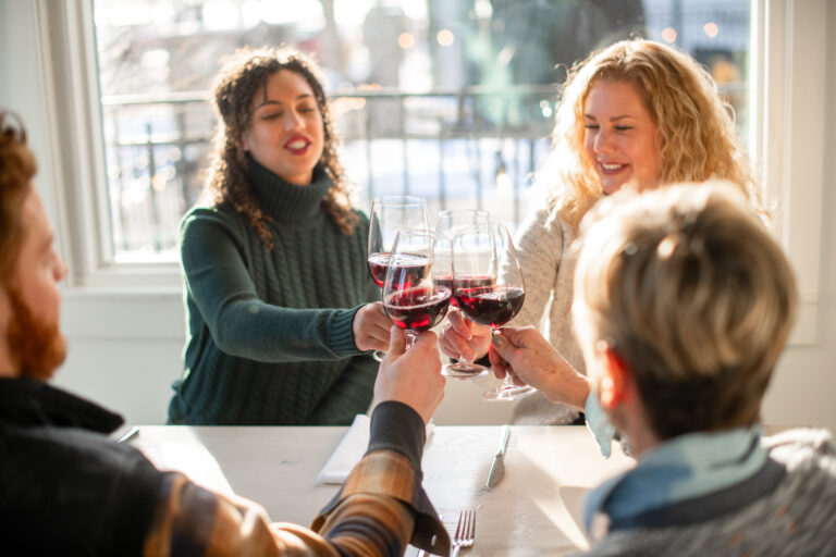 Four friends toasting with wine at a restaurant.