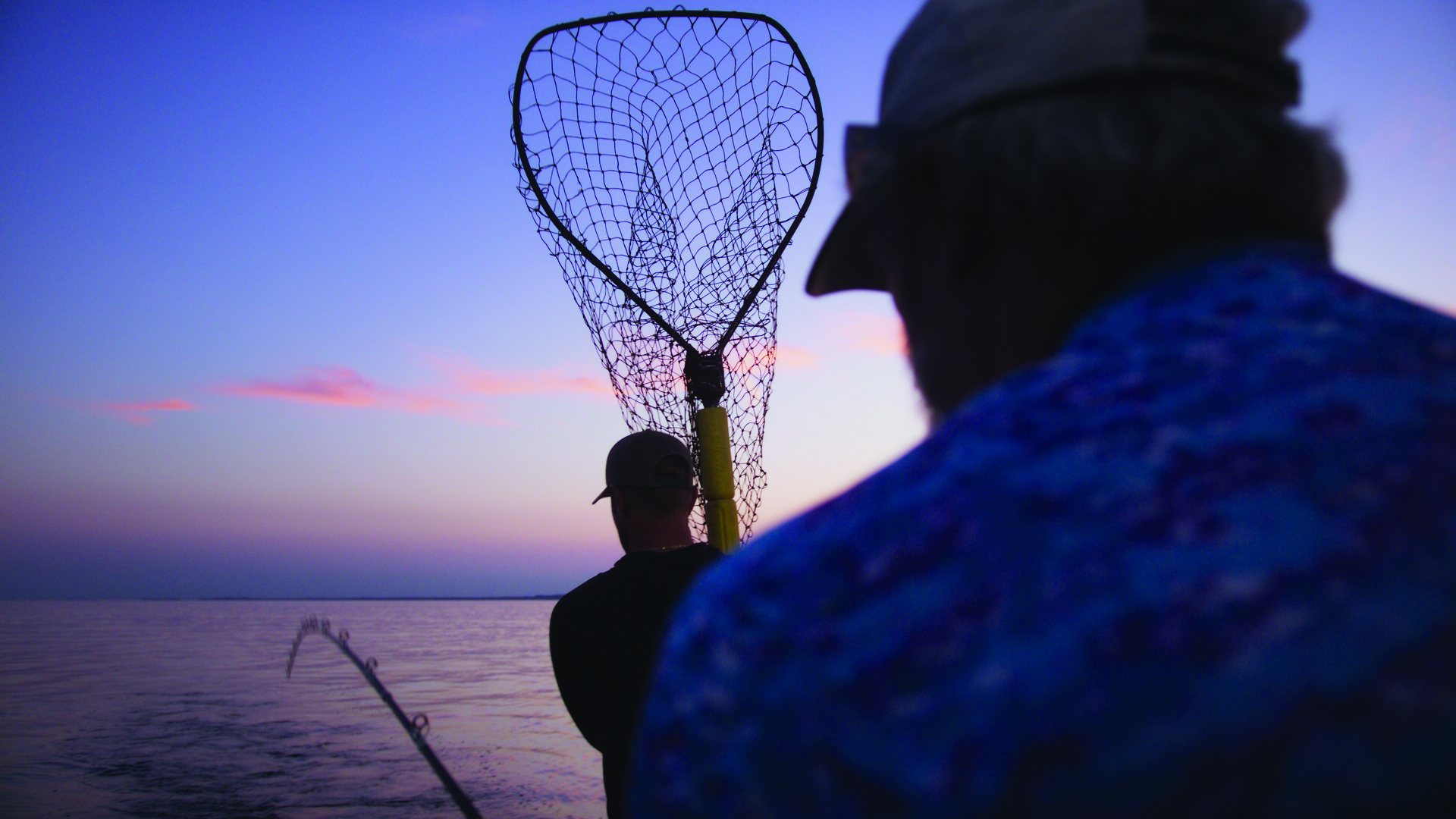 A man holding a net on a charter fishing trip.