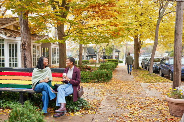 A couple enjoying drinks on a bench in downtown Saugatuck.