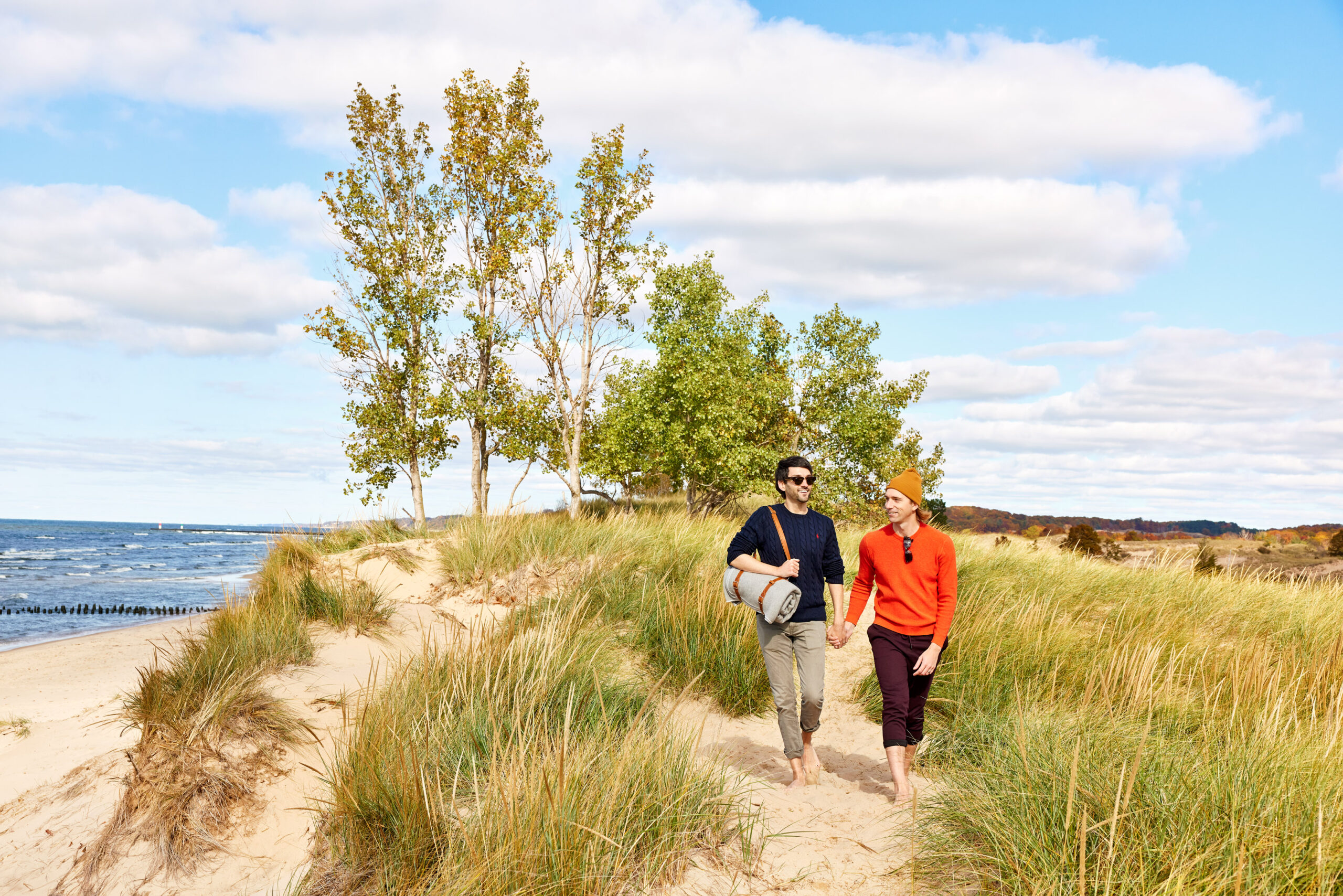 A couple holding hands and hiking the dunes of Saugatuck Harbor Natural Area.