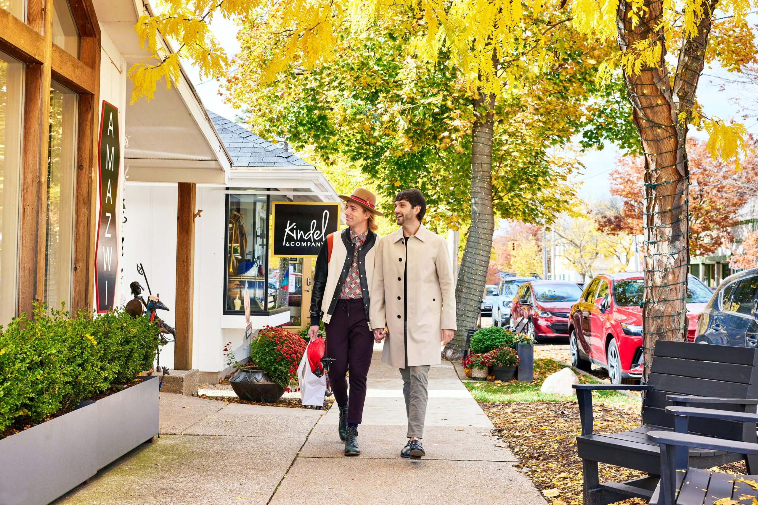 A couple window shopping in downtown Saugatuck. Golden fall trees and colors are in the background.
