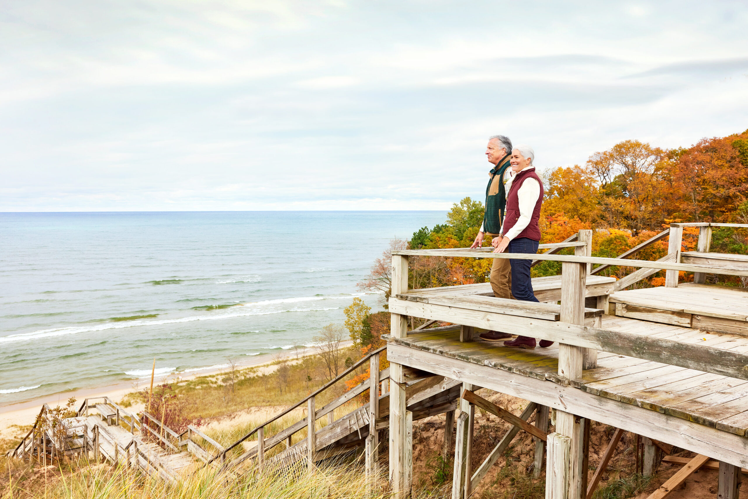 A couple looking off a dune stairway at Laketown Beach in the fall.
