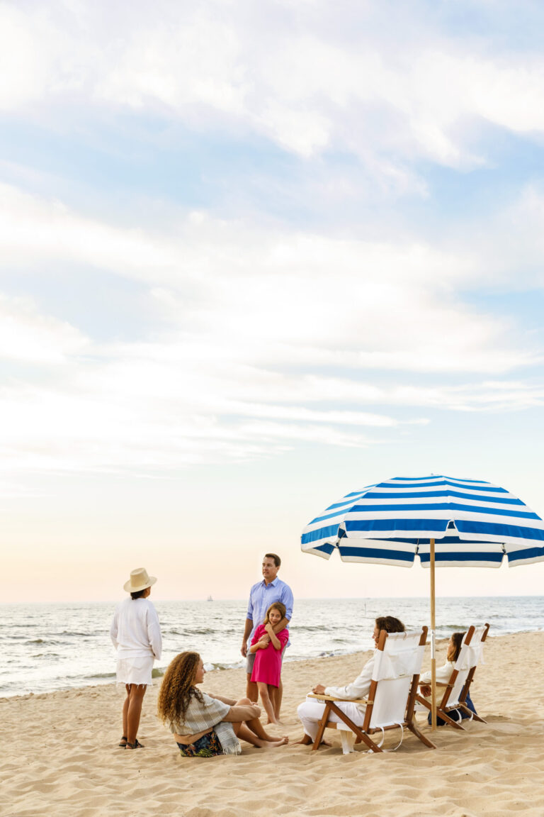 A family relaxing under an umbrella on the shore of Oval Beach.