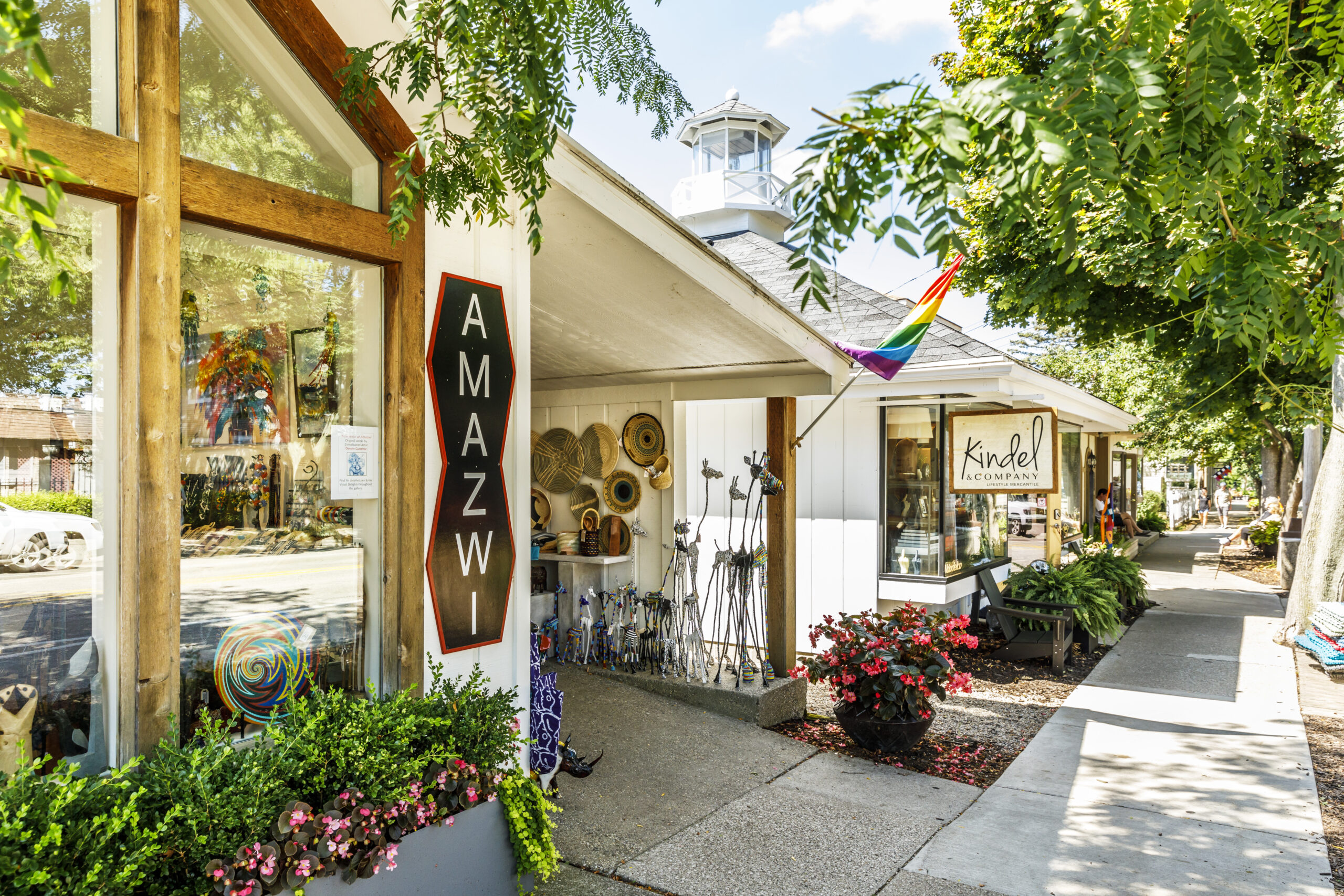 A block of shops and boutiques in downtown Saugatuck. A pride flag is hanging outside.