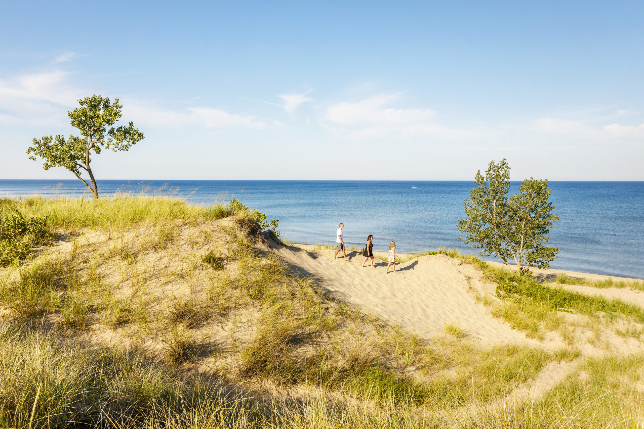 A family of three hiking the shore of Saugatuck Dunes State Park.