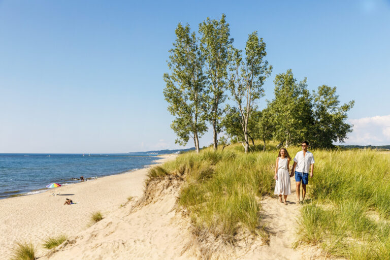 A couple hiking along the shore of Oval Beach.