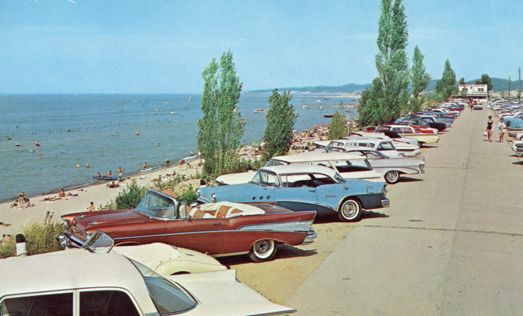 A historic image of 1950s cars and people on a beach.