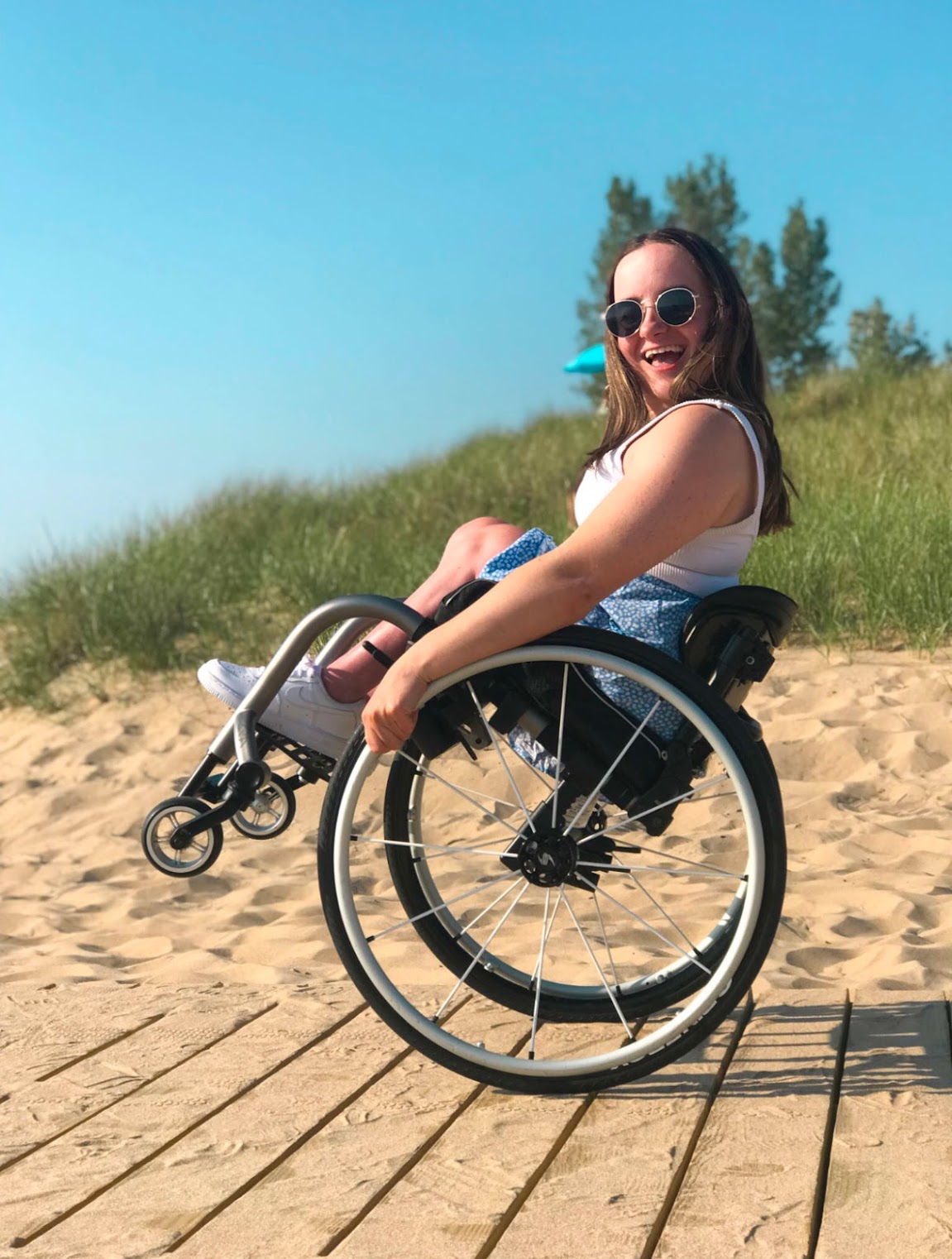 A woman smiling on the Oval Beach boardwalk while in her wheelchair.