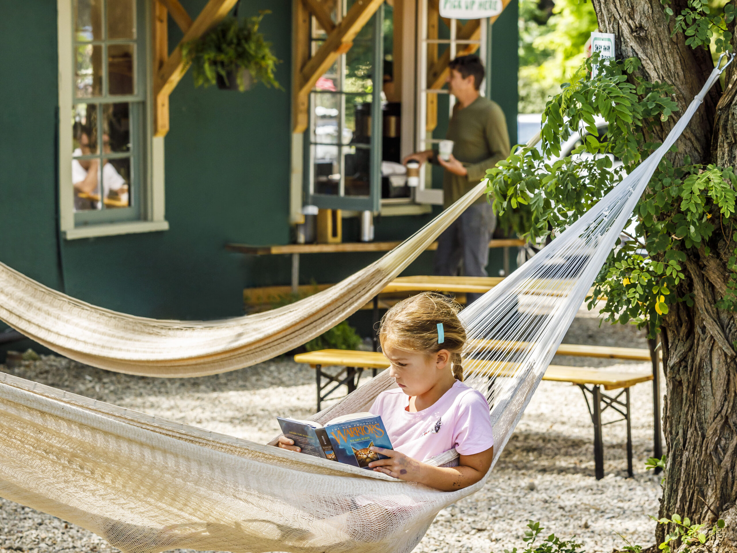 Little girl reading in a hammock outside of Outside Coffee