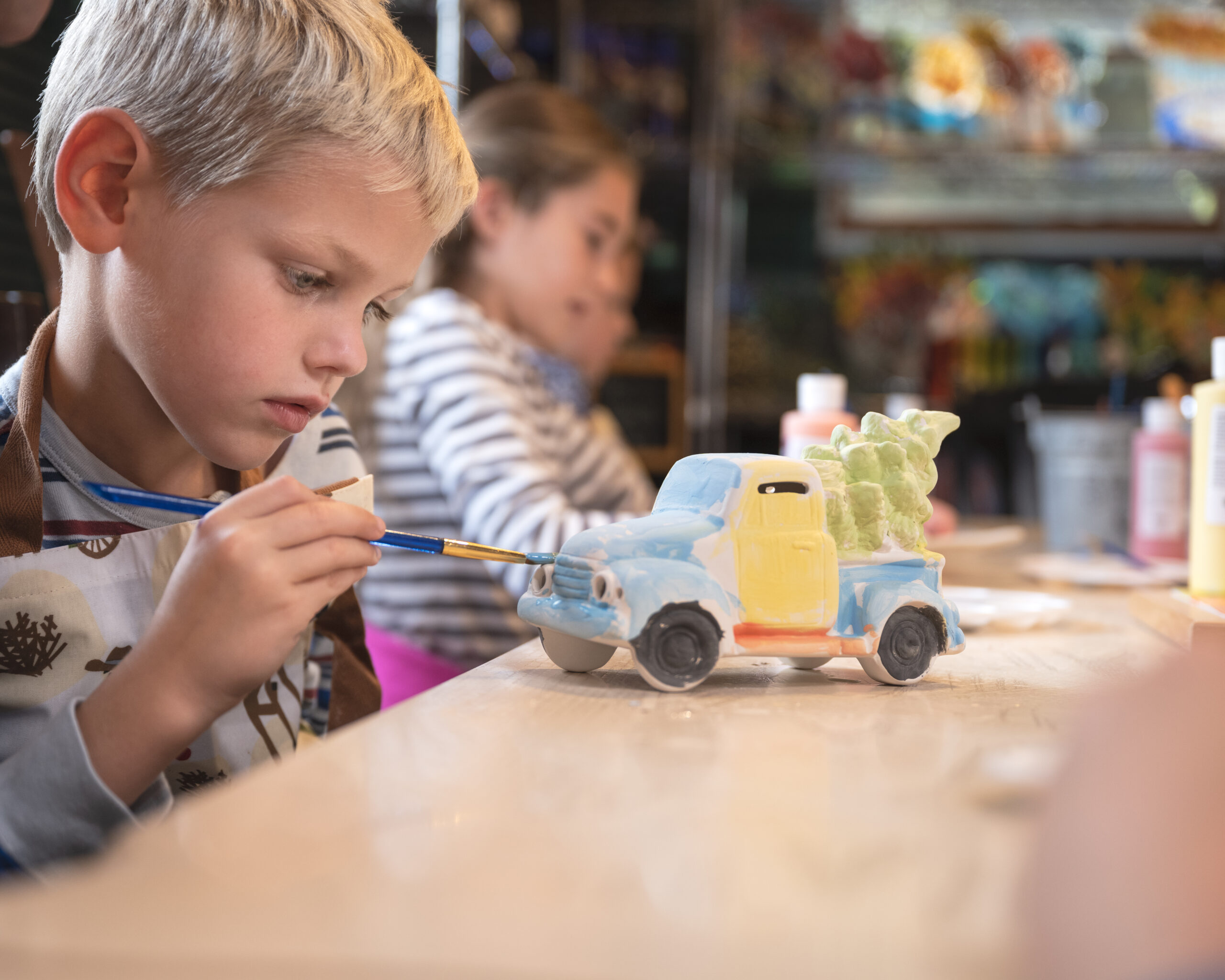 Child painting ceramic truck at the Art Barn